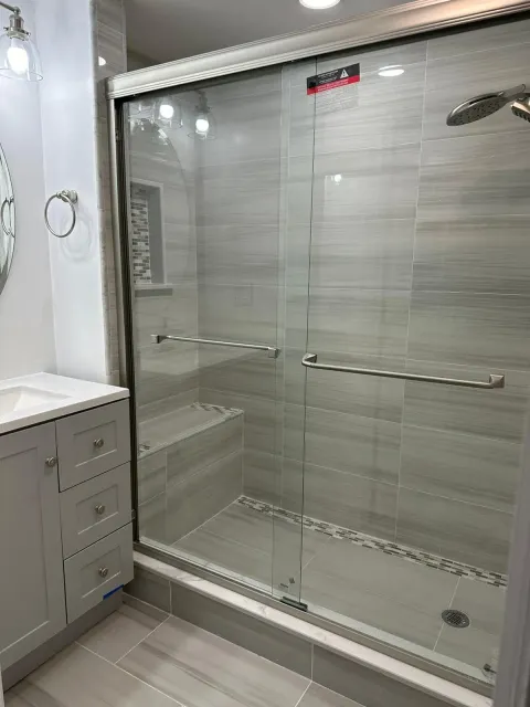 a bathroom with a sliding glass shower door and a sink .