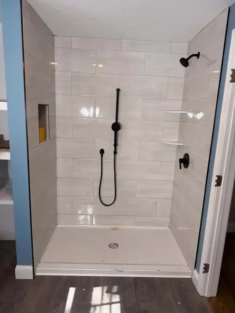 Contemporary walk-in shower with black fixtures and tiled walls.