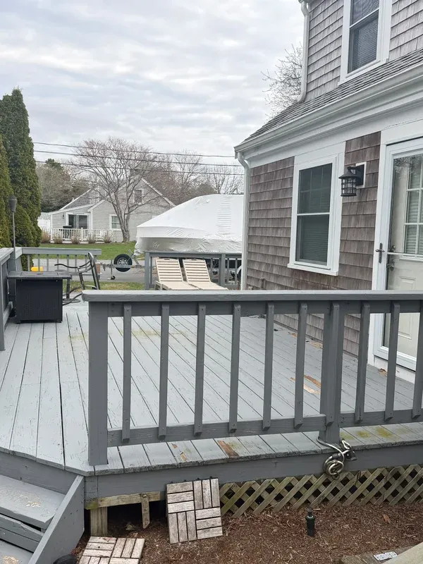 Gray deck with darker railing and steps beside the house
