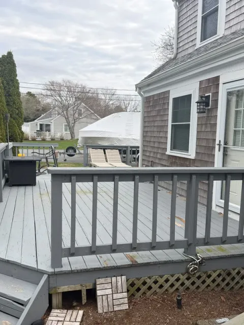Gray deck with darker railing and steps beside the house