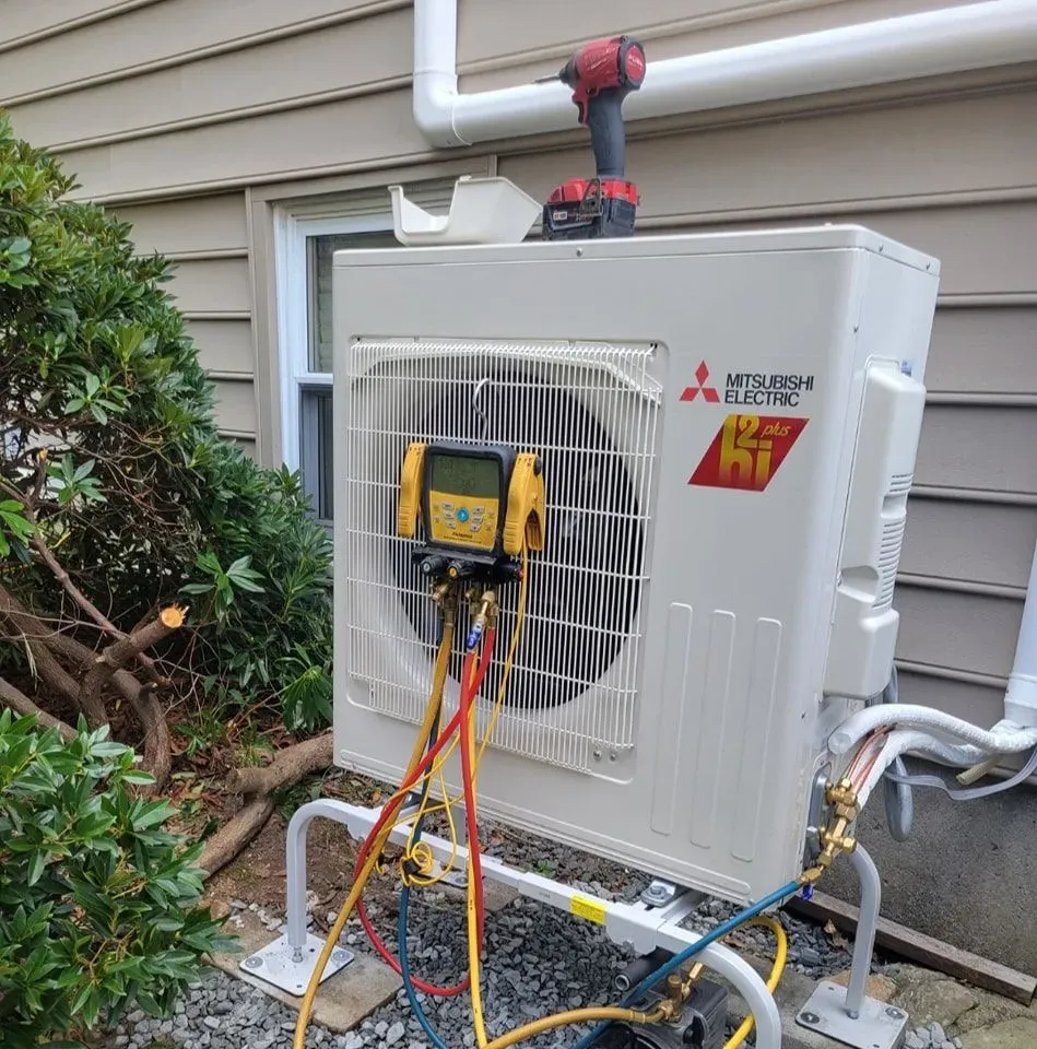 A mitsubishi electric air conditioner is being installed on the side of a house.