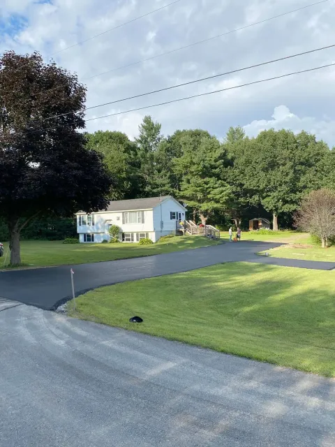 A white house with a newly paved driveway