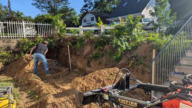 Worker performing manual excavation with Empire mini excavator in residential backyard
