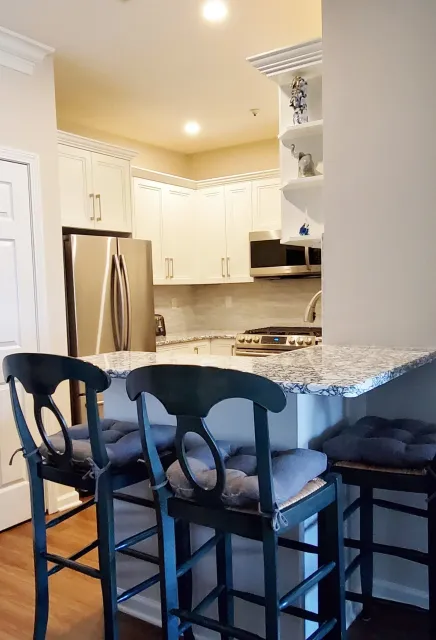 A kitchen with two bar stools and a granite counter top.