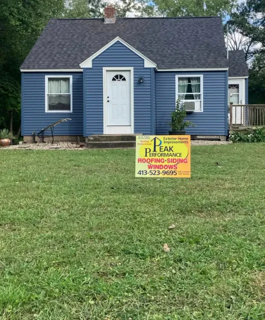 Blue house with a front lawn and a yard sign offering landscaping services