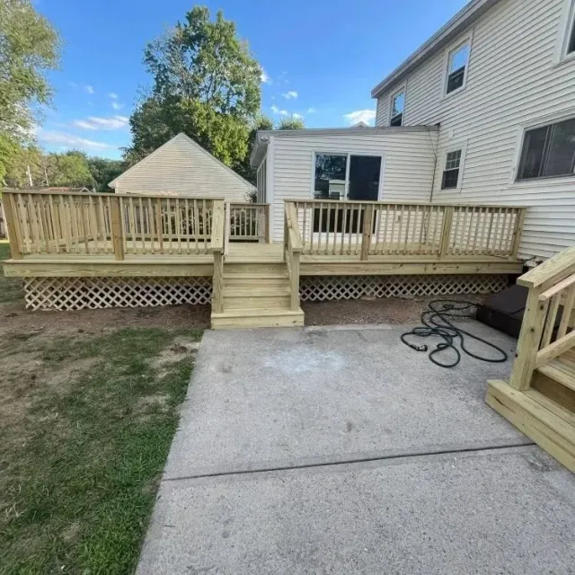 Backyard deck with steps and ramp area beside a house, with patio and fence railings