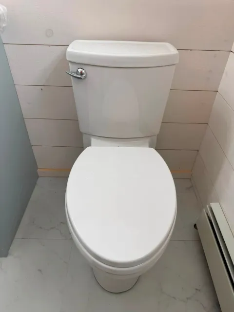 White toilet in a small tiled bathroom, viewed from above.