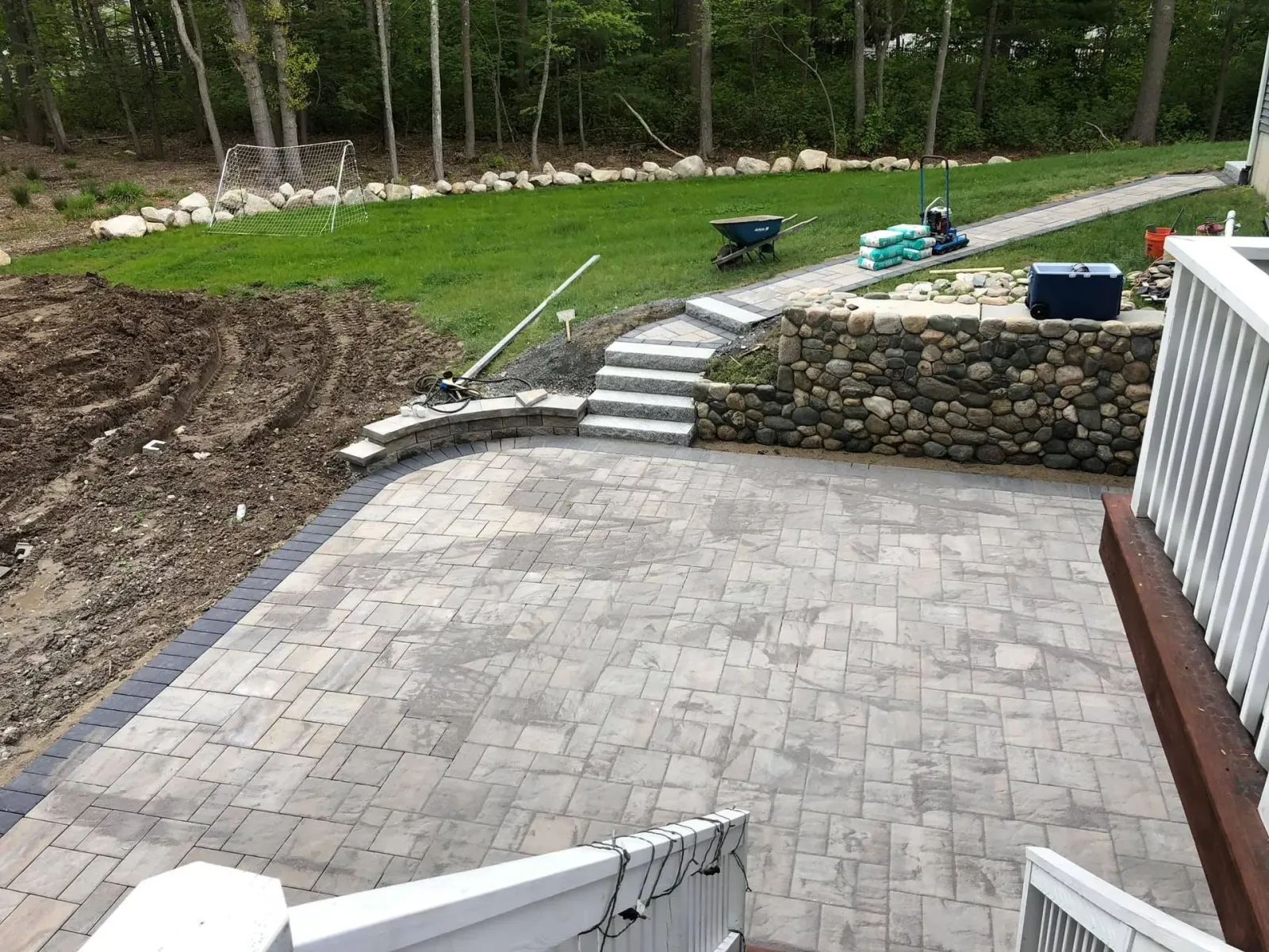 A patio with stairs leading up to it is being built in a backyard.