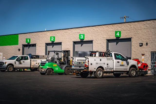 Lupo Electric service trucks and equipment staged outside industrial facility with four loading bays