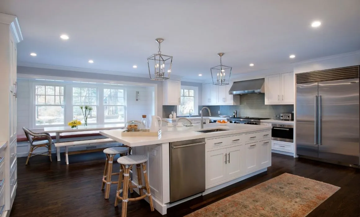 Photo of kitchen with white cabinets, island, and pendant lights - Woodland Builders, South Shore MA.