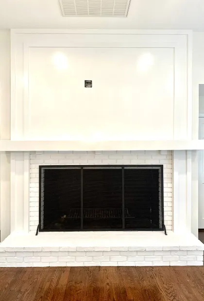 A fireplace with white brick and black tile surround.