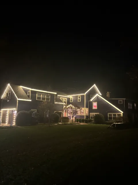 A beautiful home in Concord Mass is well lit with warm white Christmas lights at night. A cozy holiday vibe!
