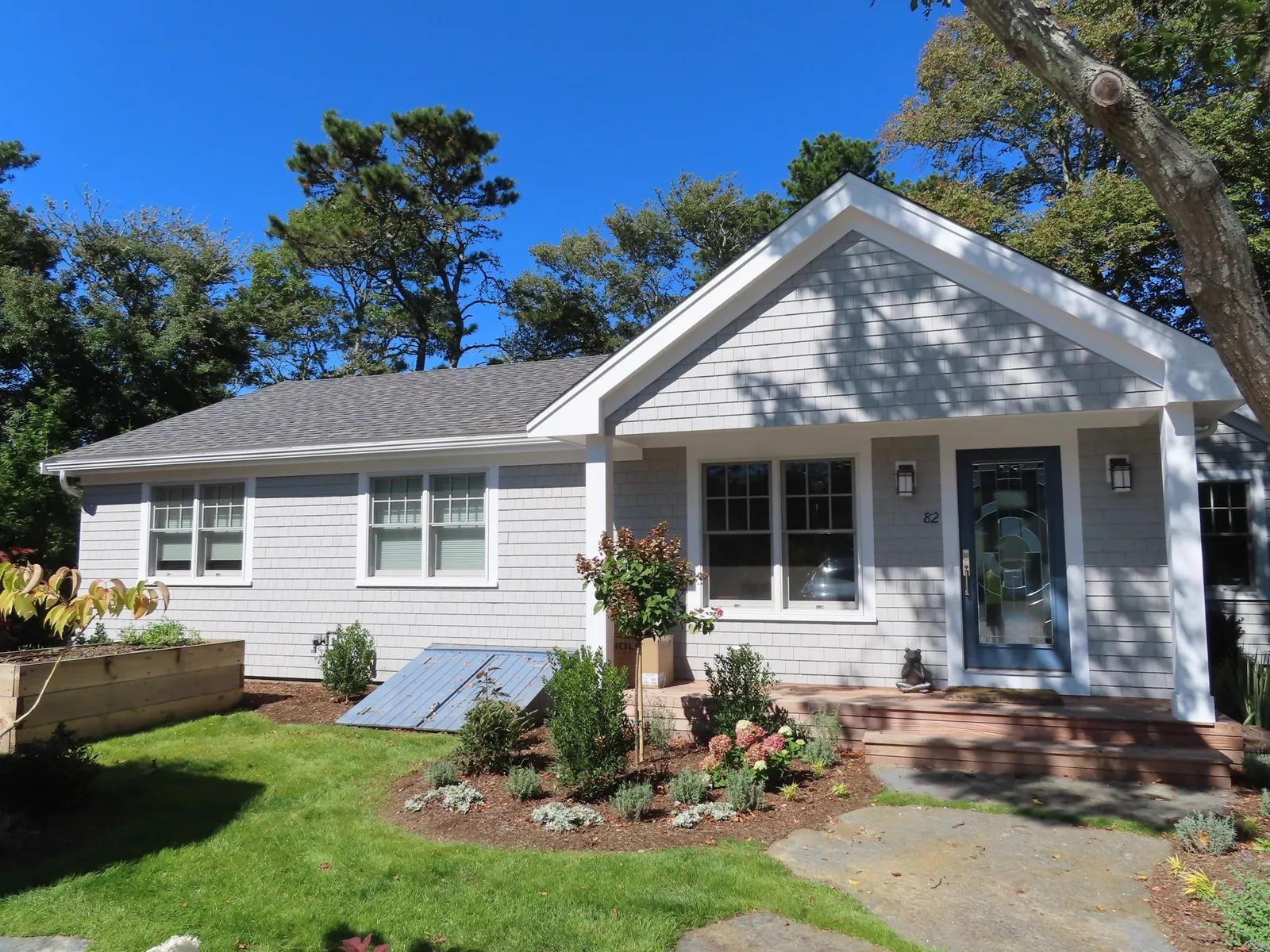 A small cute ranch-style home with bulkhead visible and attractive landscaping
