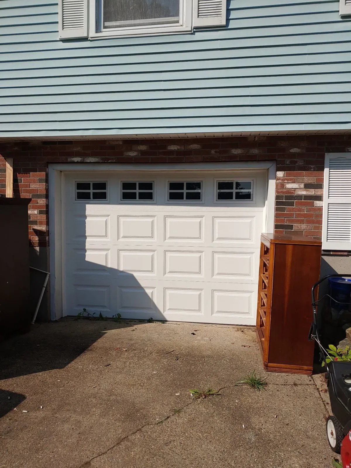 White garage door on a brick building, surrounded by discarded furniture and gravel.