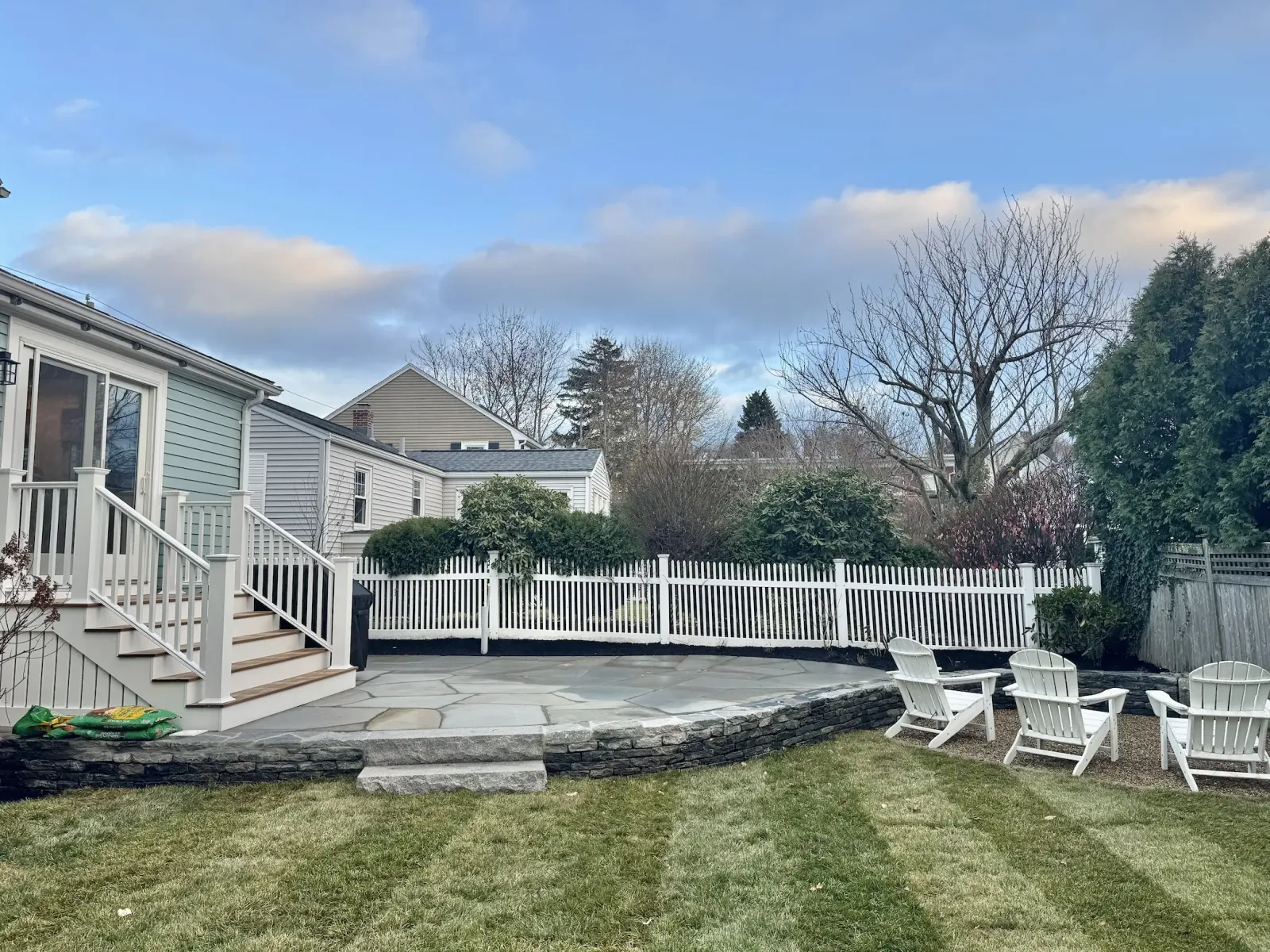Raised irregular bluestone patio hardscaping with lawn and seating area by Lasana's Landscaping