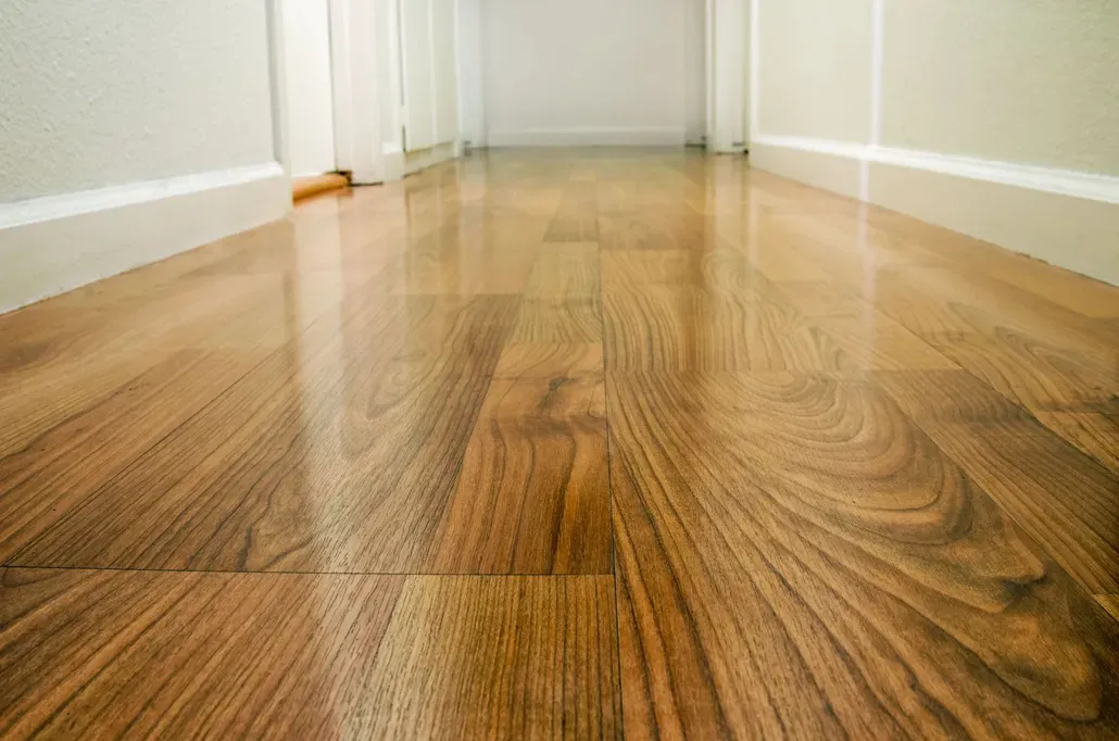 Shiny hardwood floor in a hallway, reflecting light. White walls and trim.
