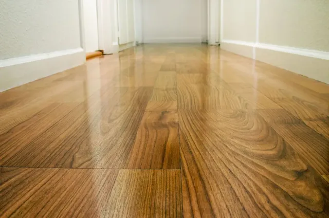 Shiny hardwood floor in a hallway, reflecting light. White walls and trim.
