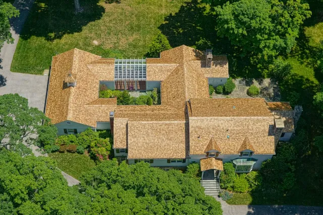 Top-down aerial view of an expansive cedar roof surrounded by mature landscaping