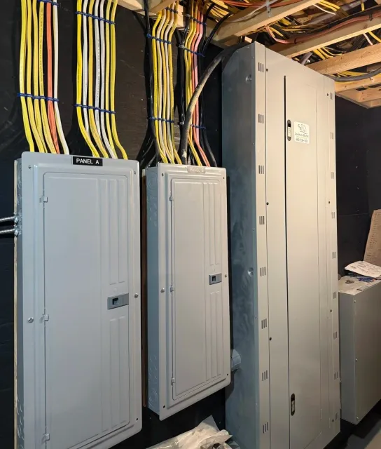 Electrical panels and wiring behind a wall, labeled Panel A and Panel B, with various colored wires organized and connected to the panels.