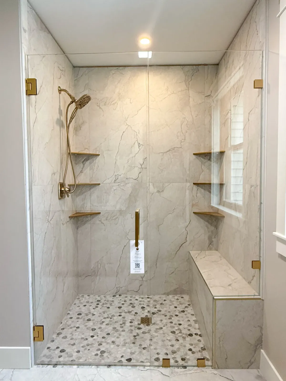 Frameless shower with gold hardware and bench