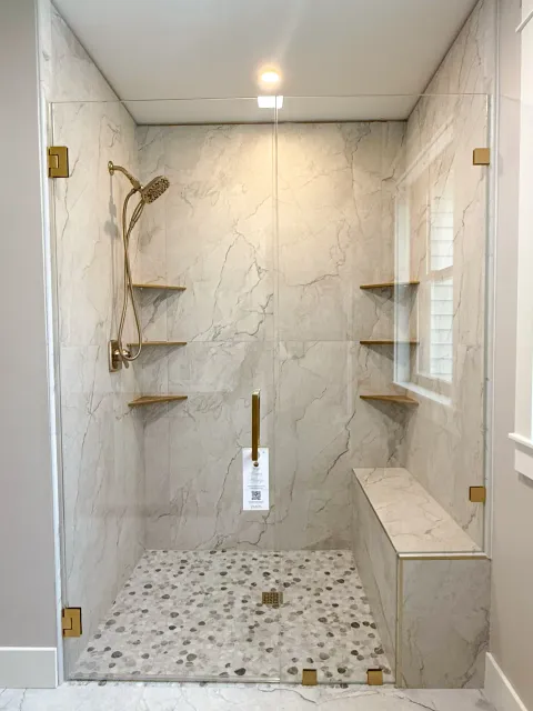 Frameless shower with gold hardware and bench