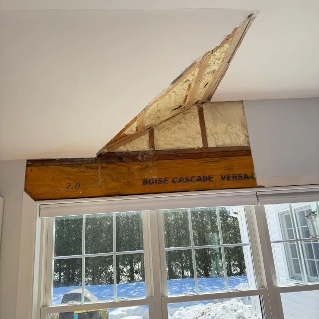 Old wooden sailboat model mounted above a window in a room