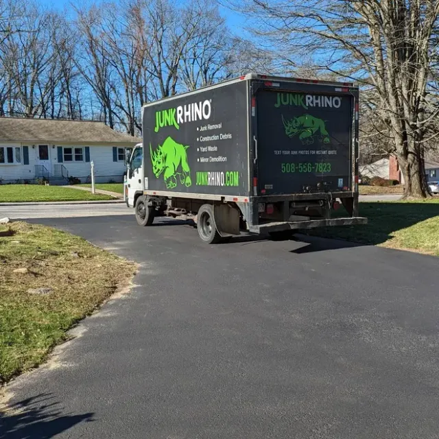 Junk Rhino truck parked on a driveway in front of a house on a sunny day.