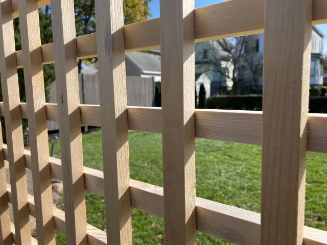 A close up of a wooden fence with a house in the background.