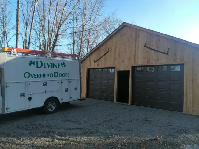 A garage with two brown doors, next to a service truck. The truck has the words