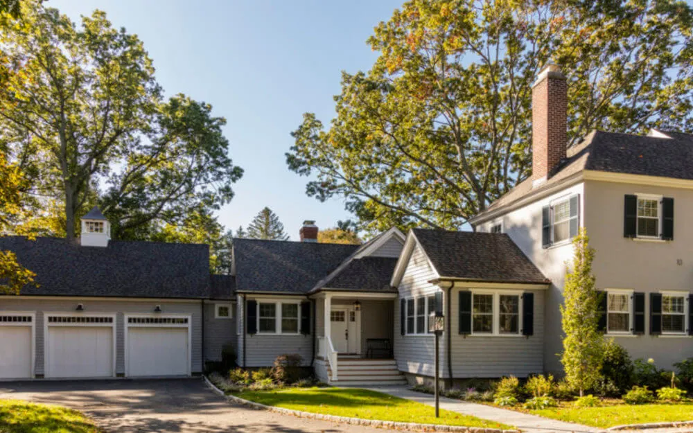 Photo of gray two-story home with white-trim garage doors - Woodland Builders, South Shore MA.