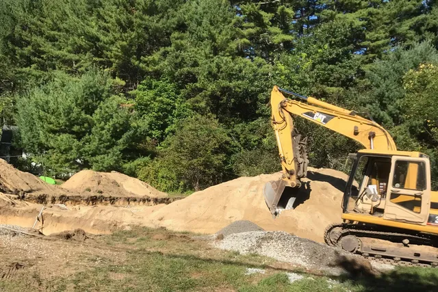 A yellow and black tractor is parked on some dirt