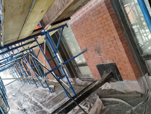 A row of scaffolding is sitting in front of a brick building