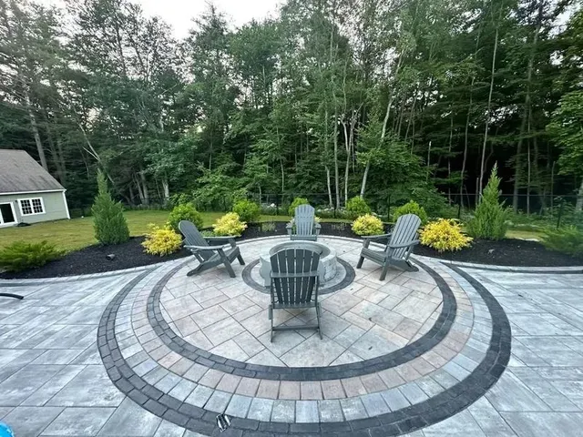 Circular paved patio with fire pit, surrounded by Adirondack chairs and landscaping.