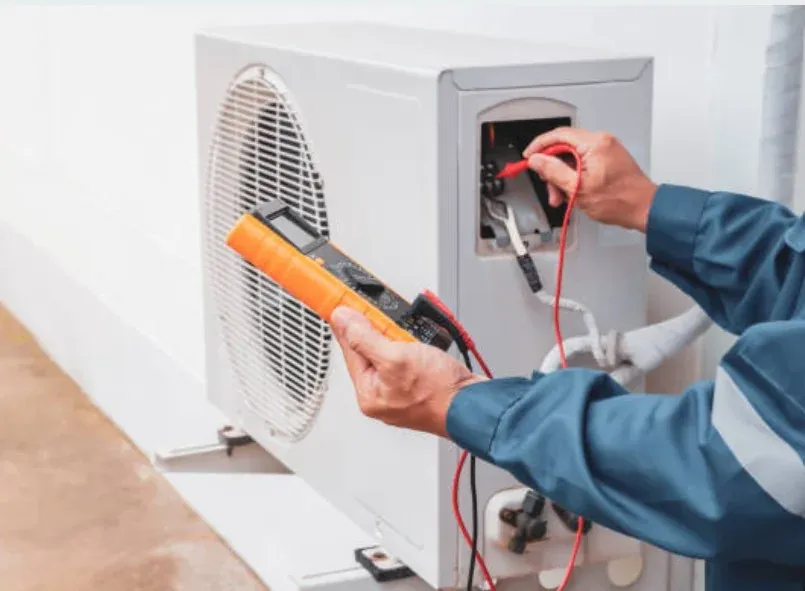 Technician model testing a residential outdoor HVAC unit with a multimeter