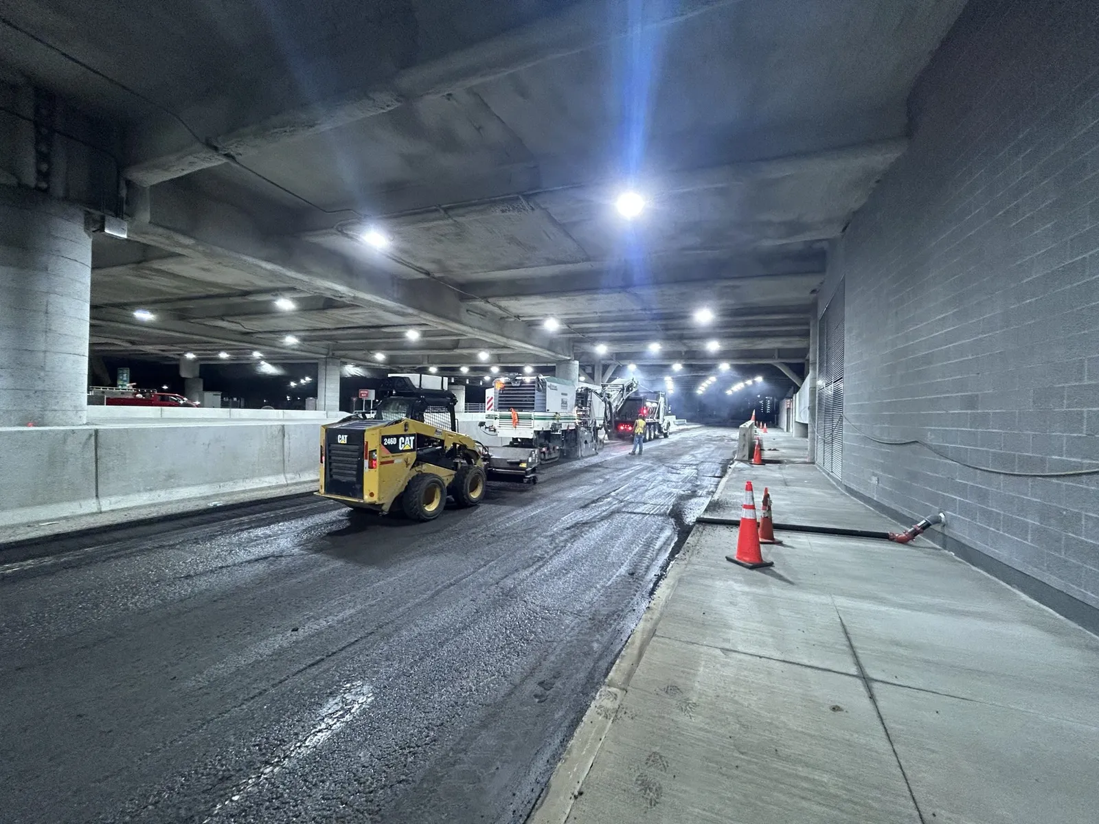 Walsh Contracting Corp performing nighttime roadway milling and paving operations beneath an elevated structure during a large-scale road rehabilitation project.