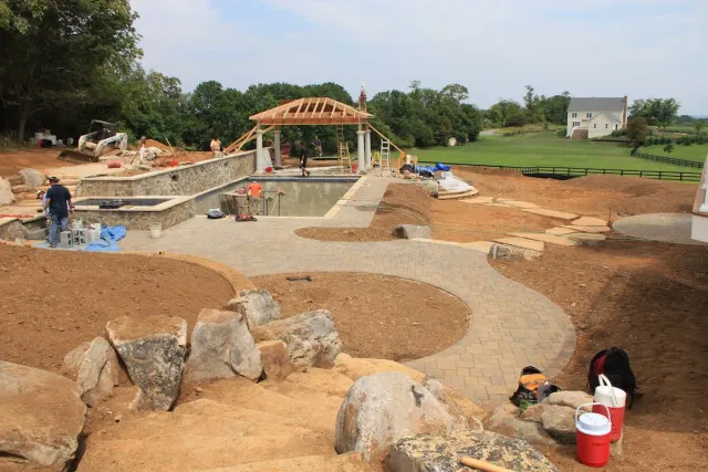 Children playing in a sandy park area with stone features and a small pavilion in the background
