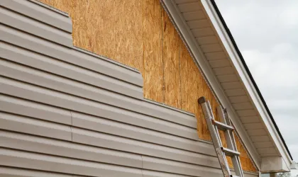 ladder leaning against the house with ongoing siding installation