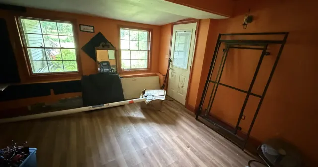 Early-stage interior room remodel showing exposed subfloor and framing before renovation