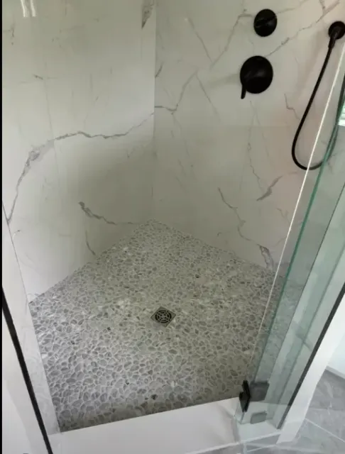 Close-up detail of a pebble stone shower floor from the same project