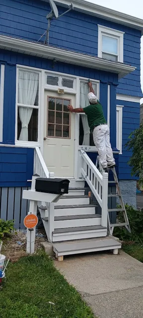 Professional painter working on blue house exterior in New Bedford MA - NG Painting Pro residential painting
