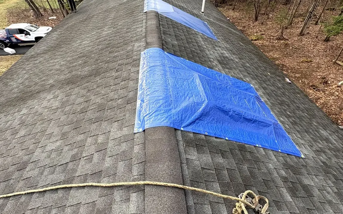 Storm-damaged roof under emergency tarps before A-Z Roofing replacement
