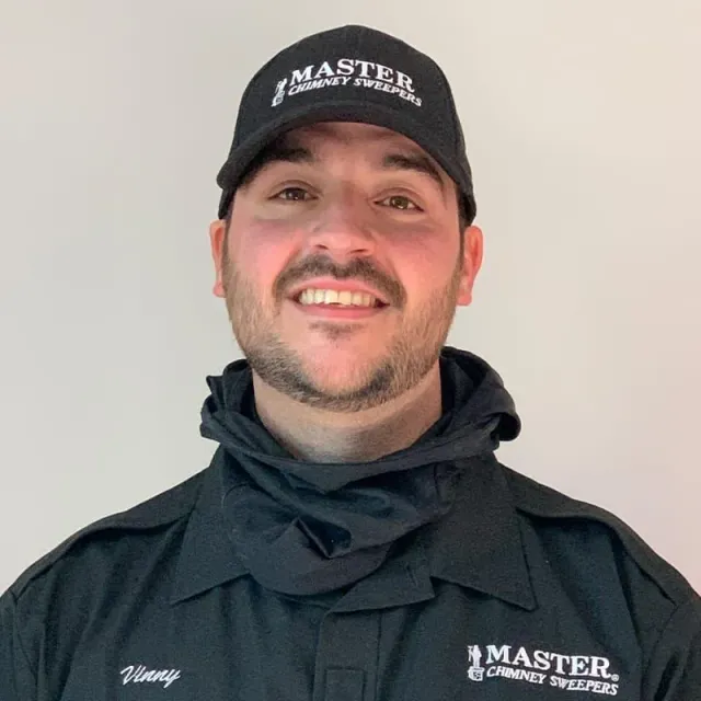 A man wearing a hat and a jacket is smiling for the camera.