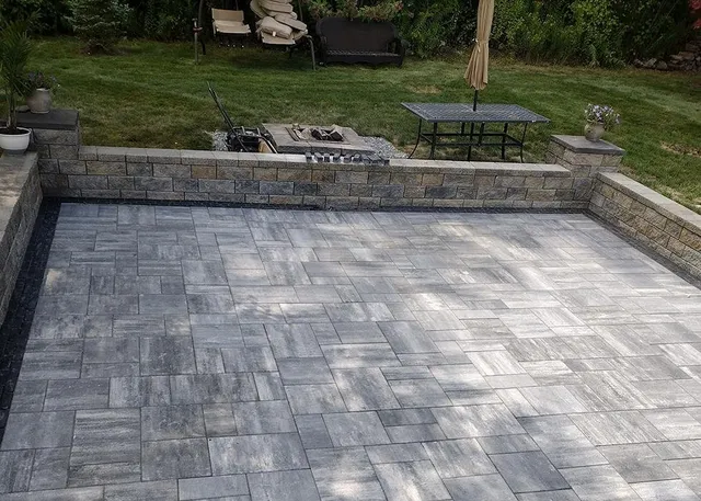 Custom paver patio installation featuring gray slate pavers in herringbone pattern with integrated hardscape design in Luster.