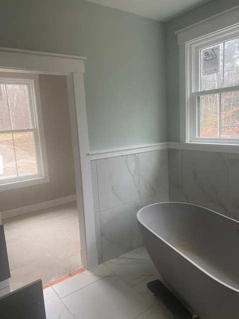 Professional painter from Paint Pros LLC carefully painting an interior wall in a Southern Maine home