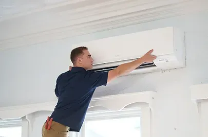 Professional HVAC installer mounting an indoor Mitsubishi air conditioning unit.