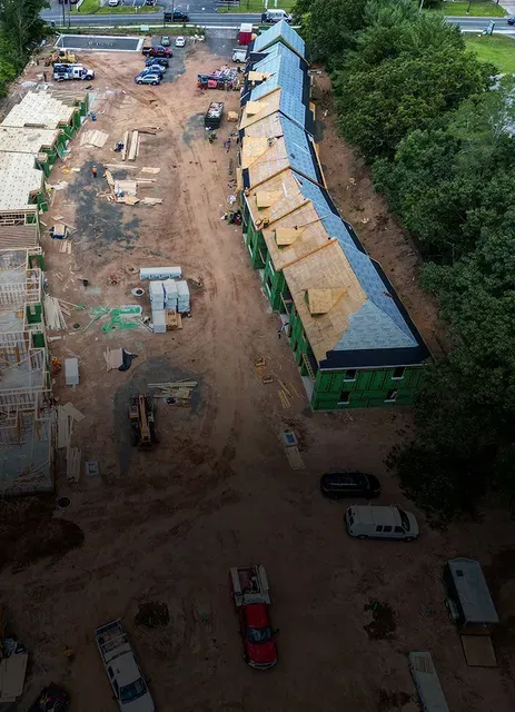 Aerial view of construction site with multiple buildings, some framed and others with roofing.