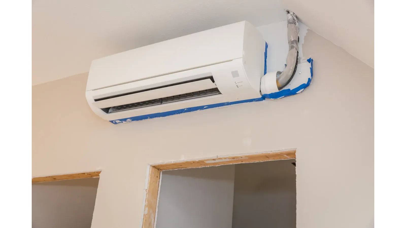 A wall mounted air conditioner is being installed in a room.