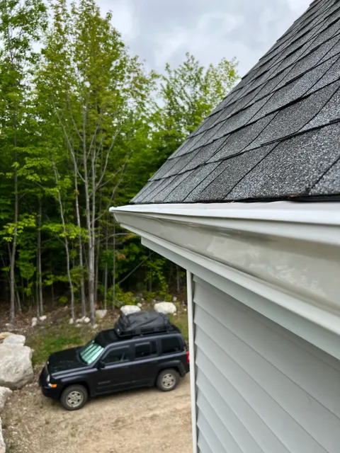 Clean white K-style gutter with New England pines