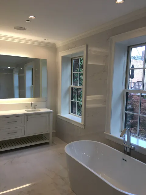 a bathroom with a tub, sink, mirror and window