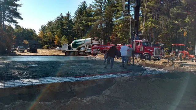 Crew placing and finishing a large concrete slab